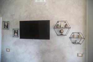 a flat screen tv hanging on a wall with three shelves at Le nove Aci in Acireale