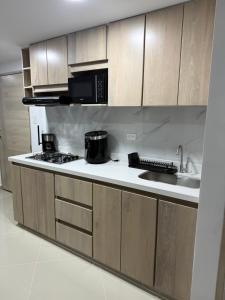 une cuisine avec des armoires en bois et un four à plaques de cuisson dans l'établissement 202 Nuevo Poblado y Provenza muy cerca, à Medellín