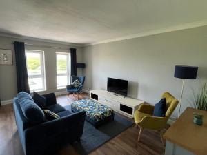 a living room with a couch and chairs and a tv at Harbour Mill Apartment in Westport