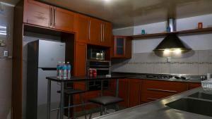 Una cocina con gabinetes de madera y un refrigerador blanco. en Casa céntrica para grupos grandes, en San Luis Potosí