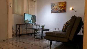Una sala de estar con un sofá, una mesa y un televisor. en Casa céntrica para grupos grandes, en San Luis Potosí