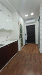 a kitchen with white cabinets and a wooden floor at VIP Apartments 9 in Odesa