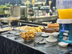 a buffet line with pastries and cakes and orange juice at Granville Hotel in Curitiba