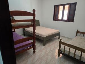 a room with two bunk beds and a bed and a window at Recanto feliz in Peruíbe