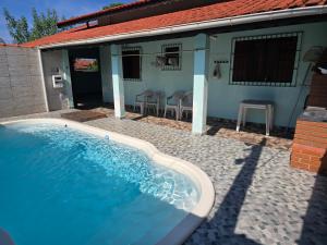 a swimming pool in front of a house at Recanto feliz in Peruíbe
