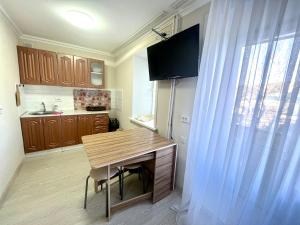 a small kitchen with a wooden table and a window at Уютная квартира-студия в курортной зоне Щучинский in Uchitelʼ