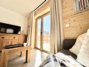 a living room with a large window and a television at Résidence Le Living Stone B - T3 RESIDENCE NEUVE, CENTRE VARS, 150m DES PISTES MAE-7681 in Vars
