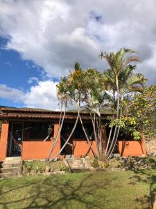 a house with palm trees in front of it at Chalés Vale Encantado -Serra do Cipó- in Jaboticatubas