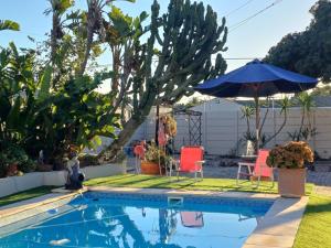 a swimming pool with two chairs and an umbrella at Stylish Studio in Tableview Stay in Cape Town