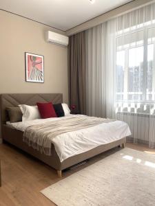 a bedroom with a bed and a large window at Студия КАКАО рядом с Арбатом in Almaty