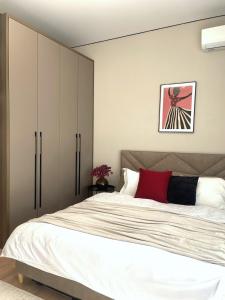 a bedroom with a large white bed with a red pillow at Студия КАКАО рядом с Арбатом in Almaty