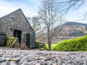 a stone house with a green shed in front of it at Holiday Home Farmburn Bothy by Interhome in Invermoriston