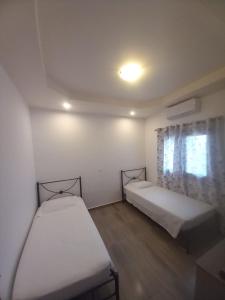 two beds in a small room with a window at Damian House in Afantou +3 photos