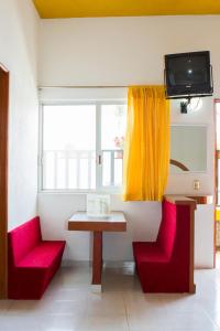 a room with two red chairs and a table and a window at Hotel Kazmay in Temixco