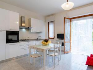 a kitchen with white cabinets and a table and chairs at Apartment Casa del Mare by Interhome in Diano Marina