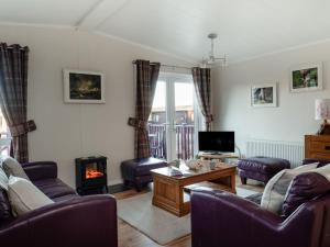 Una sala de estar con un sofá y una chimenea. en Chalet Sandpiper Lodge by Interhome, en Boat of Garten