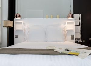 a bed with white sheets and a book on it at 1er Etage Opéra in Paris