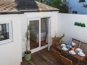 eine Terrasse mit einem Tisch, Stühlen und einem Bett in der Unterkunft Holiday Home Seaforth Cottage by Interhome in Gorran Haven