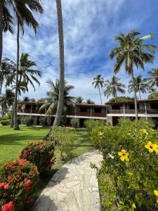 a resort with palm trees and a garden with flowers at Bitingui Praia Hotel in Japaratinga