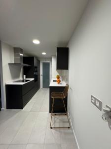 a kitchen with black and white cabinets and a stool at San Fermin Centro II in Pamplona +8 photos