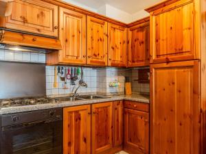 a kitchen with wooden cabinets and a sink at Apartment La Meridiana by Interhome in Spiazzo +19 photos