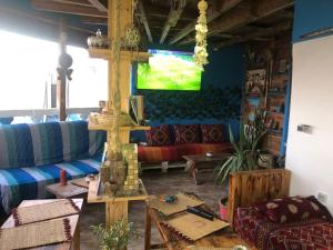 a living room with a couch and a tv on the wall at Rayane Guest House in Taghazout