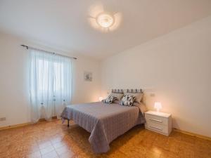 a white bedroom with a bed and a window at Apartment Viola by Interhome in Gello