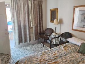 Habitación de hotel con cama, sillas y ventana en BV Motel LLC, en Searchlight