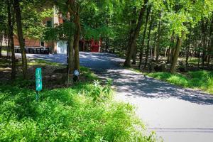 eine von Bäumen gesäumte Straße mit einem Schild im Gras in der Unterkunft Mahogany Sun Hot Tub Theater Room Fire Pit in East Stroudsburg