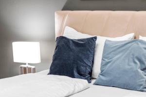 a bed with two blue pillows and a lamp at City Center I At Stadtpark I 1 Minute to Metro in Vienna +9 photos
