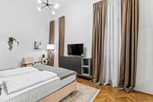 a white bedroom with a bed and a television at City Center I At Stadtpark I 1 Minute to Metro in Vienna