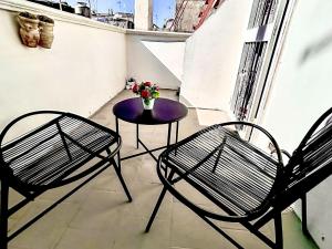 een balkon met 2 stoelen en een tafel met bloemen bij Holiday Home RomaMia by Interhome in Mola di Bari