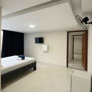 a bedroom with a bed and a tv on the wall at Hotel Veneza in Brasília