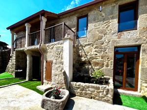 Santa MaríaAlbergue Turistico En Armenteira A Fragua do Ferreiro的带阳台和门的石头房子