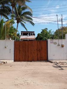 ein Holztor vor einem Zaun mit Palmen in der Unterkunft Los Chitos in Los Ayala