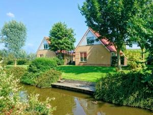 una casa con un muelle de madera junto a un río en Holiday Home in Netherlands near Scenic Parks, en Andijk