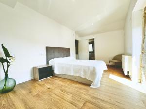 Santa MaríaAlbergue Turistico En Armenteira A Fragua do Ferreiro的一间铺有木地板的白色卧室,配有一张床