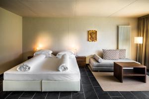 um quarto de hotel com uma cama grande e um sofá em Villa Sasso em Merano