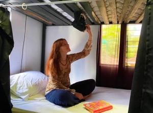 una donna seduta su un letto in una tenda di Blackout Hostel a Fortuna