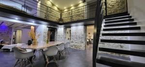 Un comedor con mesa y sillas y una escalera. en Gite le Parveau, 3 étoiles meublé de tourisme, en La Guiltière