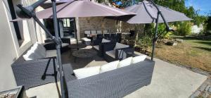 Un patio con sillas blancas y una sombrilla. en Gite le Parveau, 3 étoiles meublé de tourisme, en La Guiltière 60 fotos más