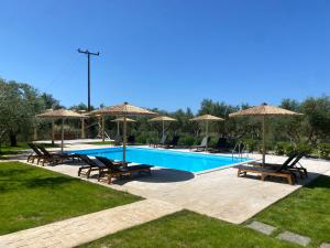 a swimming pool with chairs and umbrellas and a pool at Three Charites Resort in Gialova
