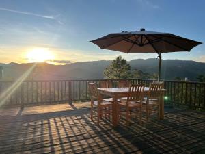 a table and chairs on a deck with an umbrella at Chácara das Palmeiras - 16 min do Capivari in Campos do Jordão