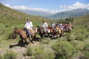 a group of people riding horses down a hill at Estancia Las Tacanas in Tafí del Valle