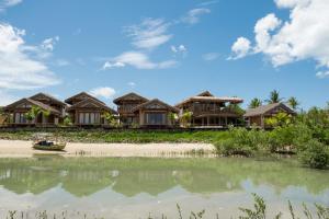 a house on the beach with a boat in the water at K08 Bangalôs in Galinhos