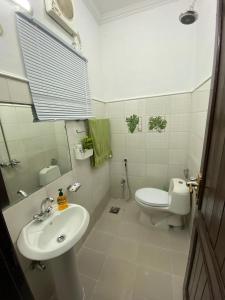 a white bathroom with a sink and a toilet at Evergreen Escape in Lahore +9 photos
