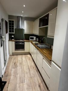 a kitchen with white cabinets and a wooden floor at Cosy Wee Cottage in Monkton