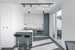 a kitchen with white cabinets and a counter with stools at Mokos Modern Suite with Sea View and Jacuzzi in Dubrovnik