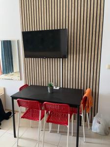 una mesa negra con sillas rojas y un televisor en la pared en Harmony Hills Tomovi Apartment A12, en Rogachevo