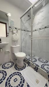 a bathroom with a toilet and a glass shower at Hotel Paipa Inn in Paipa